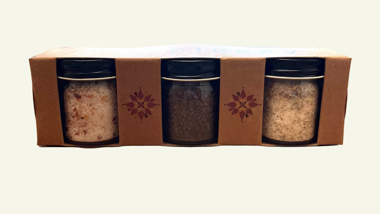 Three spice jars in a cardboard box on a wooden surface