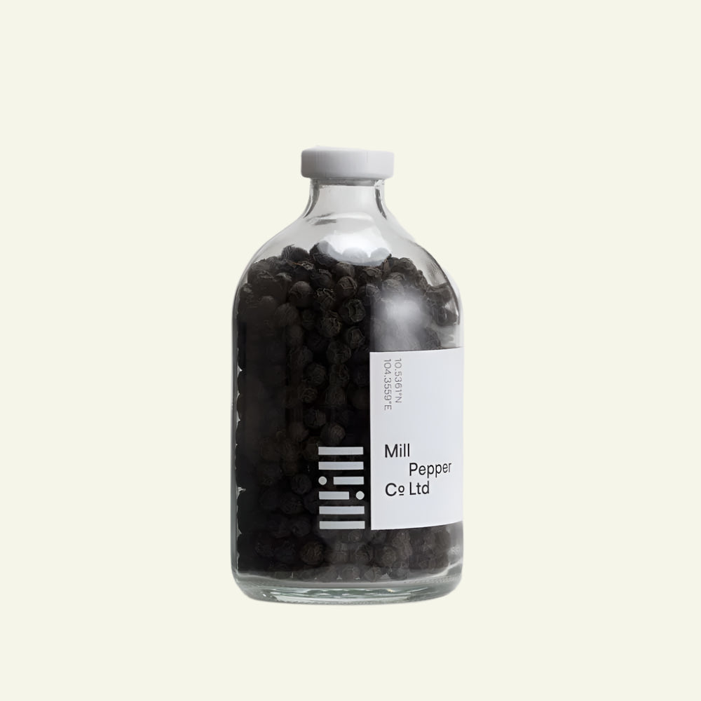 Glass bottle filled with black peppercorns on a white background