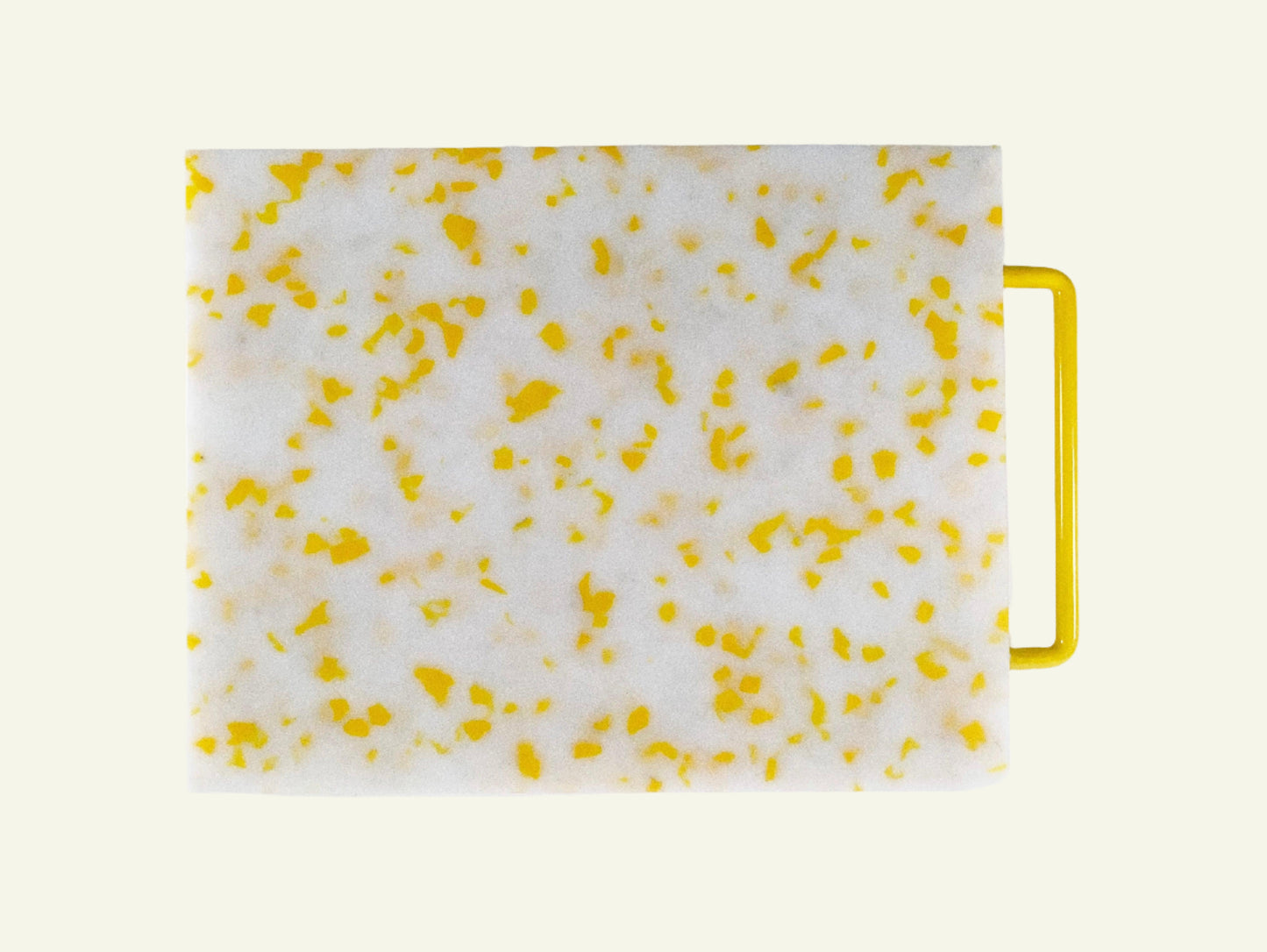 White cutting board with yellow speckles and a yellow handle on a white background
