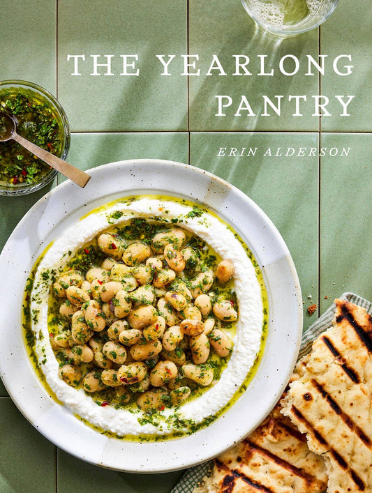 Book cover of 'The Yearlong Pantry' with a dish of chickpeas and herbs on a green tiled background.