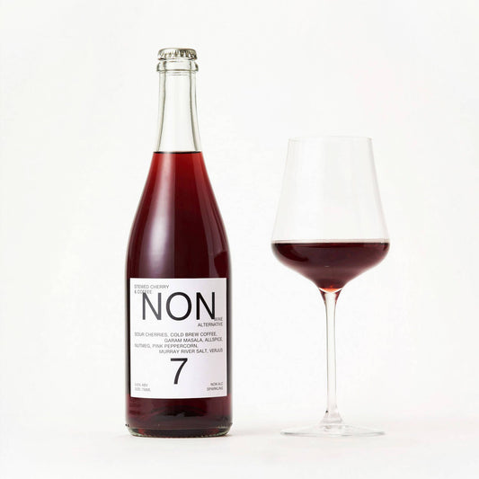 Bottle and glass of red wine with 'NON' label on a white background