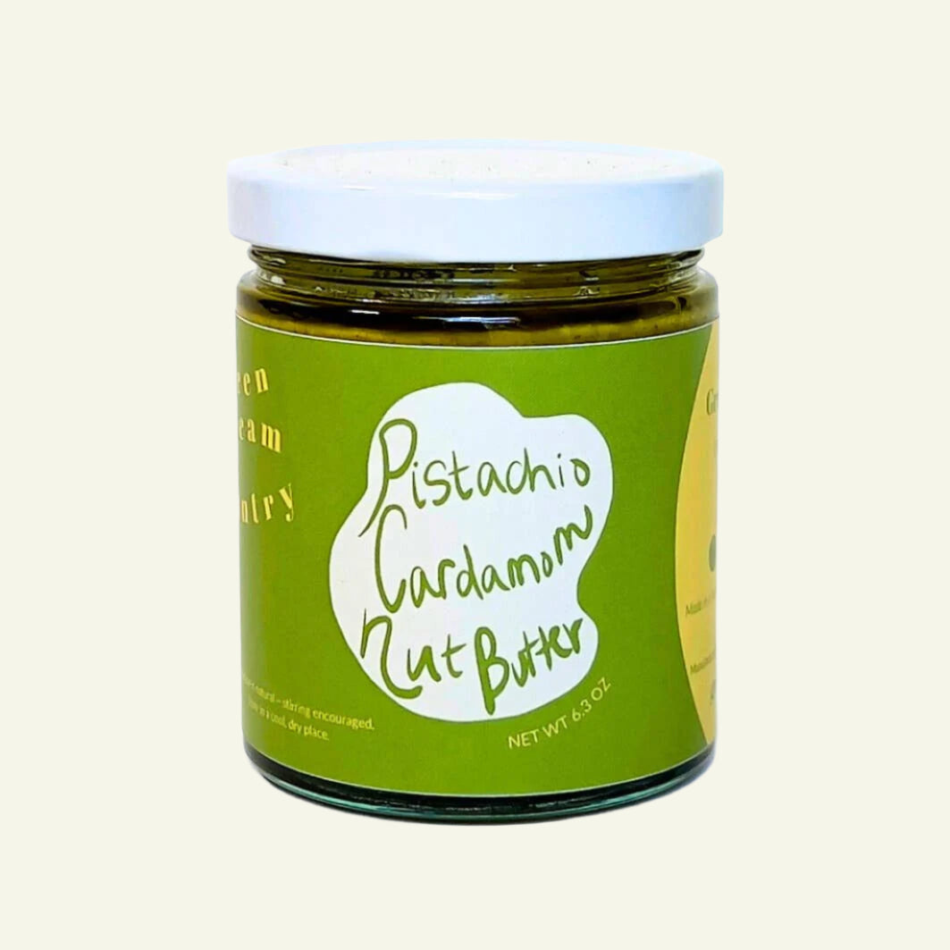 Jar of pistachio cardamom nut butter with a green label on a white background