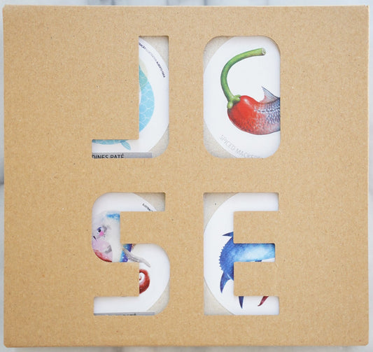 Letter-shaped coasters with colorful designs in a cardboard holder on a marble surface
