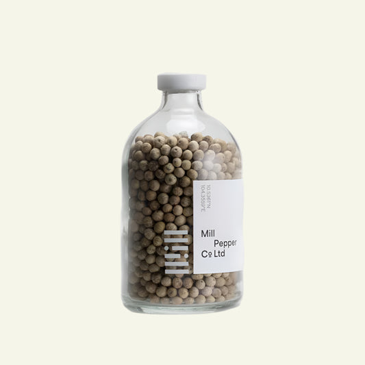 Glass bottle filled with peppercorns labeled 'Mill Pepper Co Ltd' on a white background