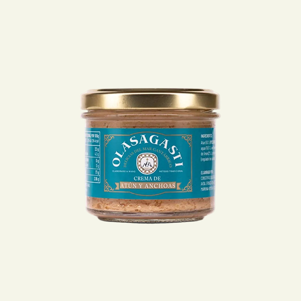 A glass jar of Olasagasti Crema de Atún Anchas (codfish anchovy cream) with a gold metal lid and a teal label, shown on a plain white background.