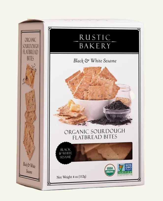 A 4 oz box of Rustic Bakery Black & White Sesame Organic Sourdough Flatbread Bites, shown at a three-quarter angle against a warm beige background.