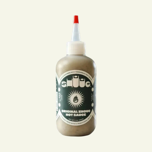 A bottle of Shuug - Zhoug Hot Sauce with a label that includes the product name and the phrase 'Original Zimbabwe Hot Sauce'.