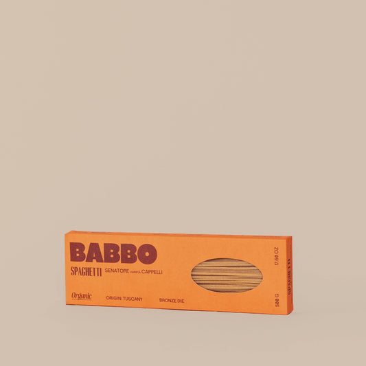 A package of Babbo spaghetti pasta with a visible window showing the dried pasta inside. The packaging is orange with the brand name and product type clearly displayed.