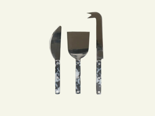 A set of three cheese knives with black and white handles, including a pointed knife, a curved knife, and a broad blade knife.